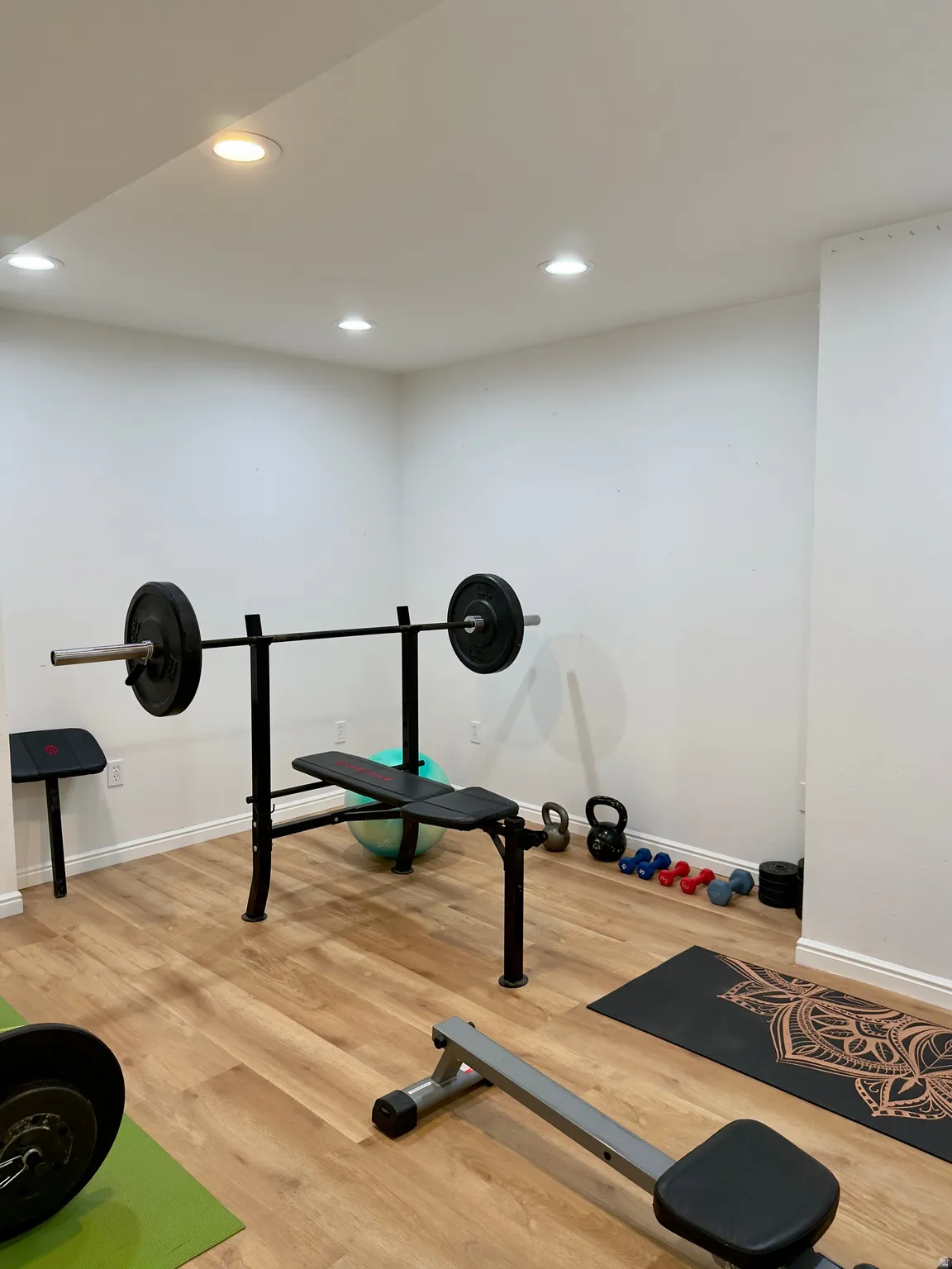 Exercise room with light wood-style floors and recessed lighting