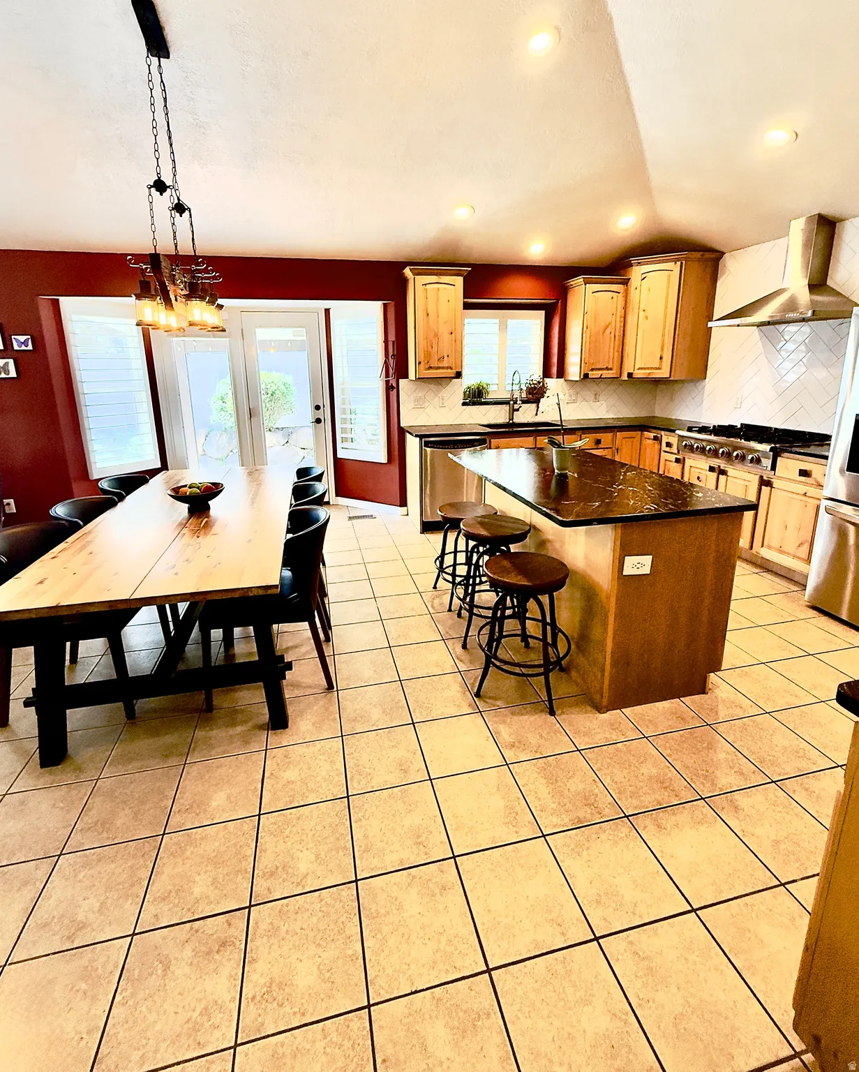 Kitchen featuring a center island, light tile patterned floors, stainless steel appliances, decorative backsplash, and vaulted ceiling