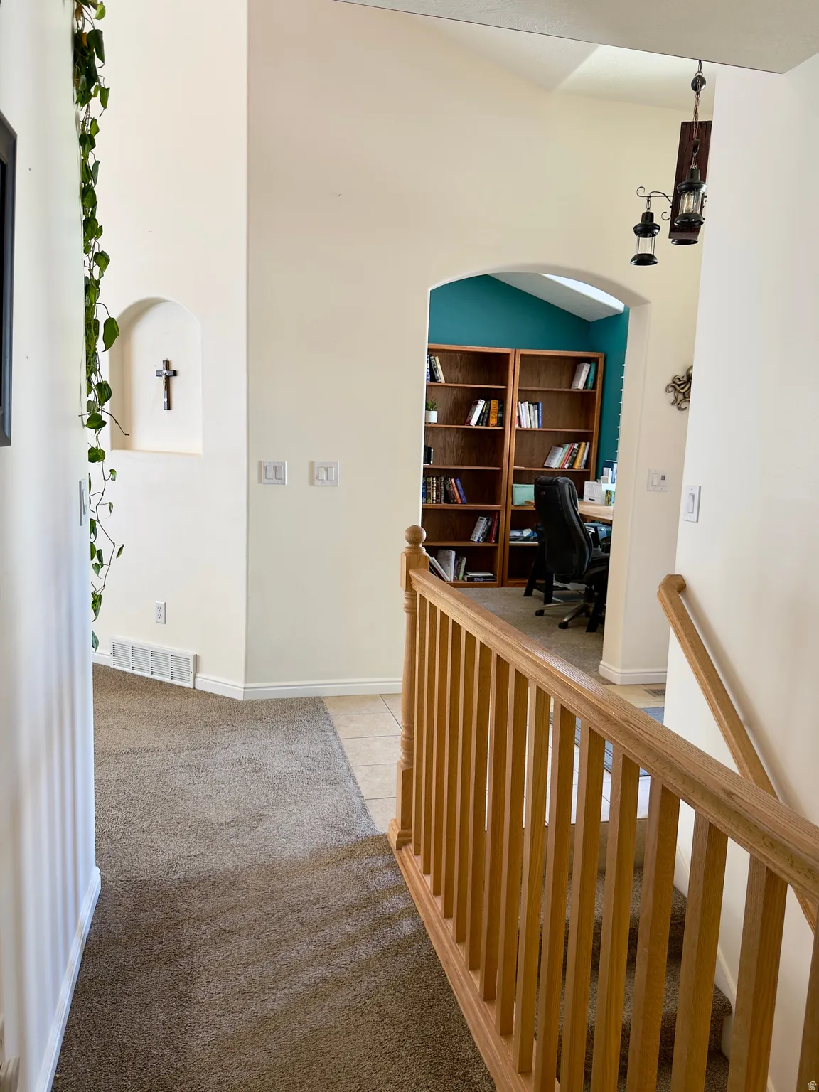 Corridor with an office area, light carpet, light tile patterned floors, and arched walkways