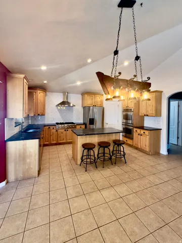 Kitchen featuring a central island with countertop seating, light wood cabinetry, recessed lighting, tile flooring, and a stainless steel appliance suite