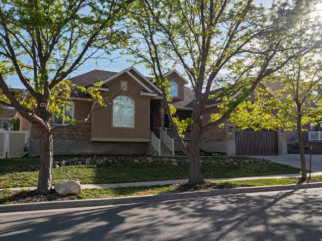 Traditional home featuring stucco siding, driveway, a shingled roof, and stone siding