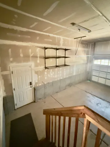 Spacious garage featuring concrete flooring, built-in shelving, a full-panel door, and a garage door with window panels
