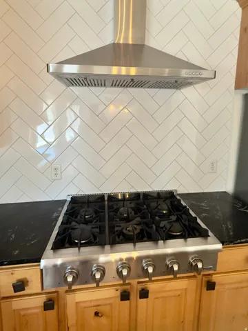 Stainless steel professional-grade cooktop with six burners, complemented by a coordinating stainless steel range hood