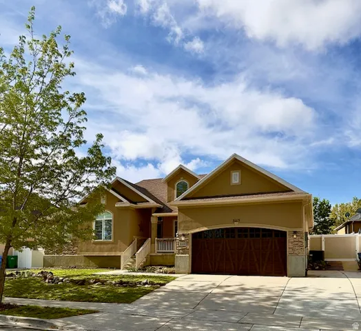 View of front of property with stucco siding, a garage, and driveway