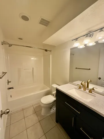 Bathroom featuring a black vanity with a light-colored countertop, an integrated sink, and gold-finish fixtures