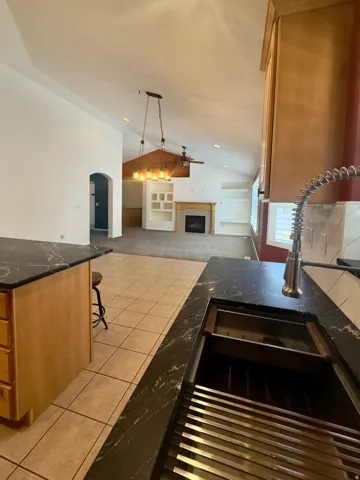 Kitchen featuring black granite countertops and a stainless steel sink with an integrated drying rack