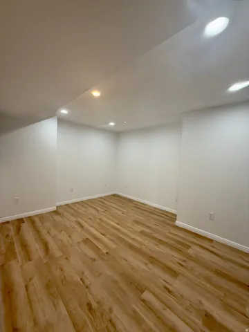 Spacious room featuring wood-finish flooring and recessed lighting