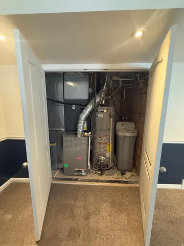Utility closet featuring a water heater, furnace, and water softener