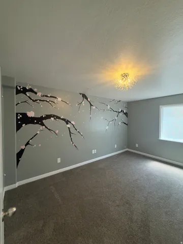 Room featuring a decorative wall mural, neutral-toned carpeting, a contemporary ceiling light fixture, and a window providing natural illumination