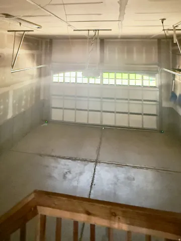Spacious garage featuring a concrete floor, an overhead garage door with upper-level windows, and an automatic garage door opener