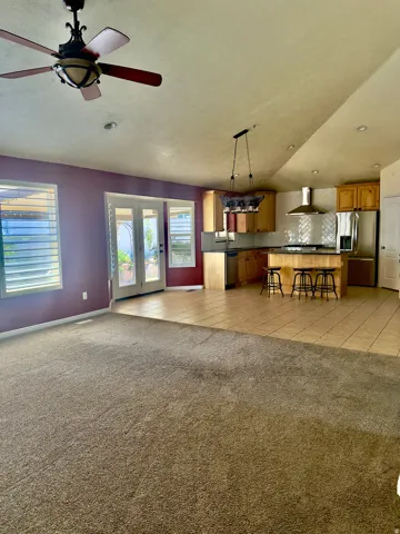 Open-concept living area with carpeted flooring transitioning to tile