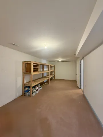 Expansive room featuring built-in wooden shelving, neutral walls, and a light brown floor