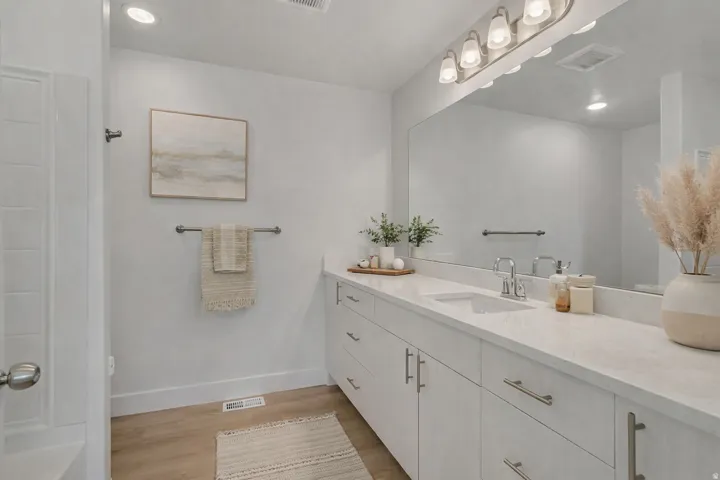Full bathroom featuring light wood-style floors, vanity, and recessed lighting