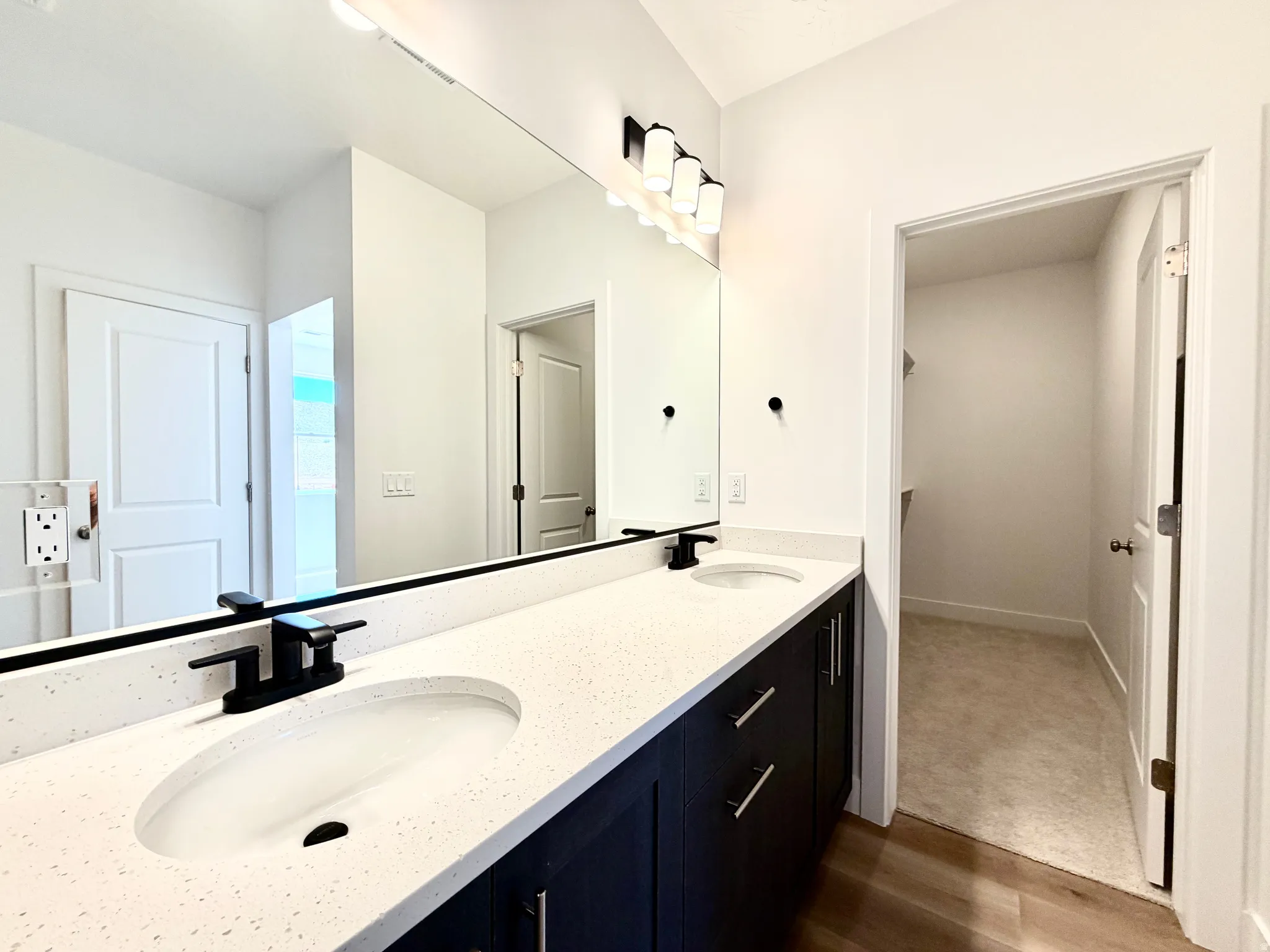 Double vanity featuring white countertops with integrated sinks, matte black faucets, and dark cabinetry