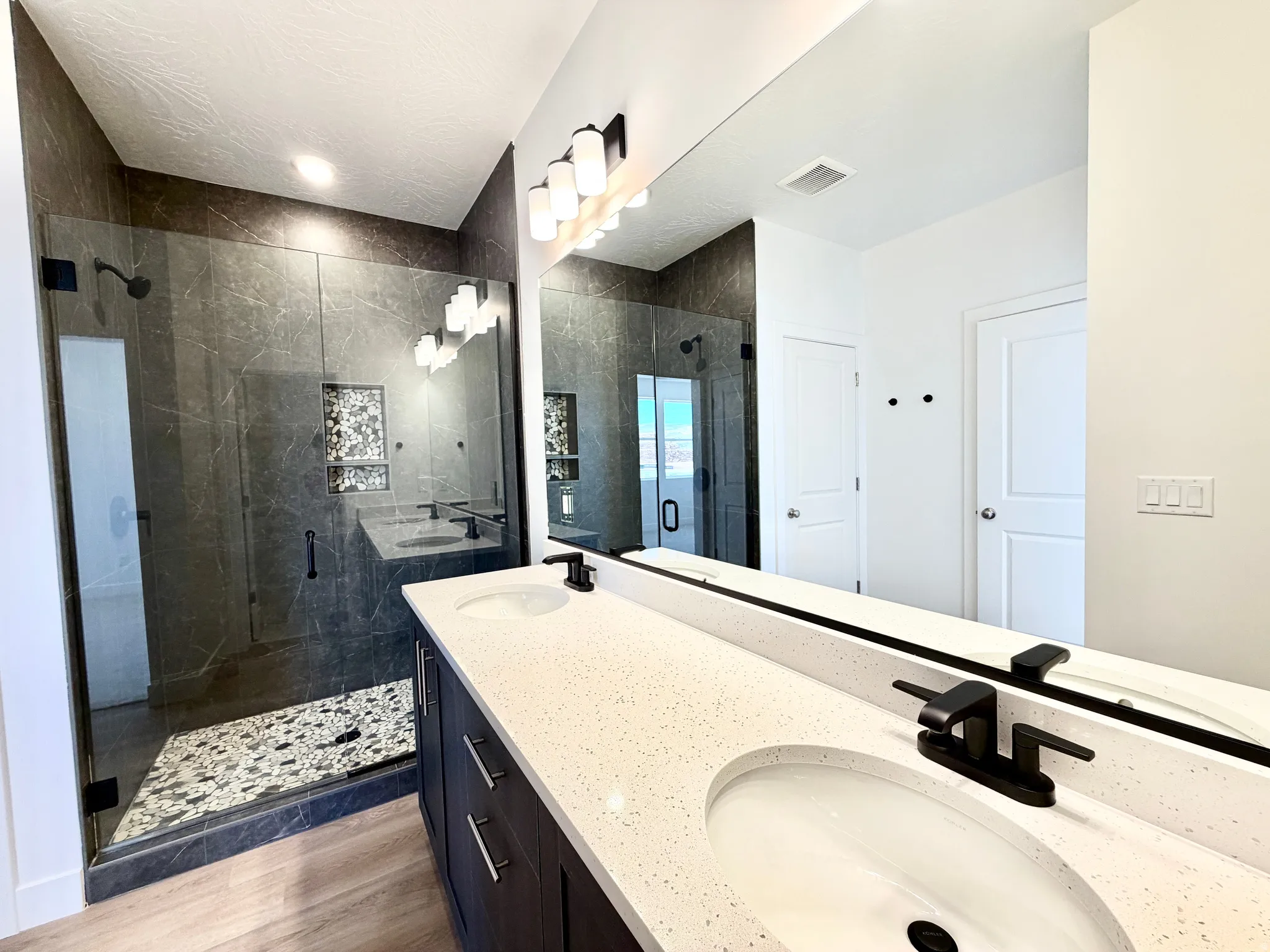 Contemporary bathroom featuring a dual vanity with white countertops, integrated sinks, and matte black faucets