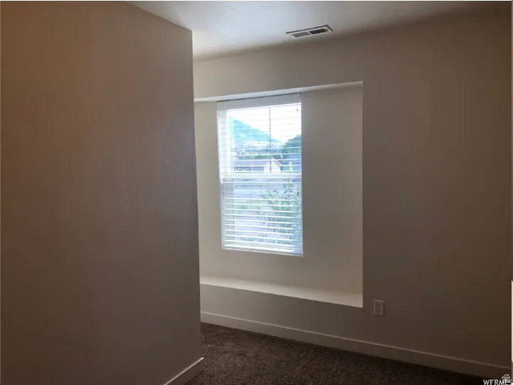 Empty room featuring dark carpet and baseboards
