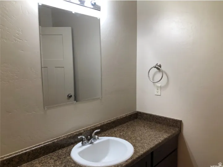 Bathroom featuring a textured wall and vanity