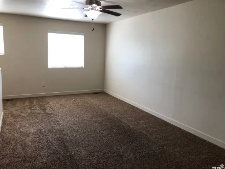 Spare room with dark colored carpet and ceiling fan