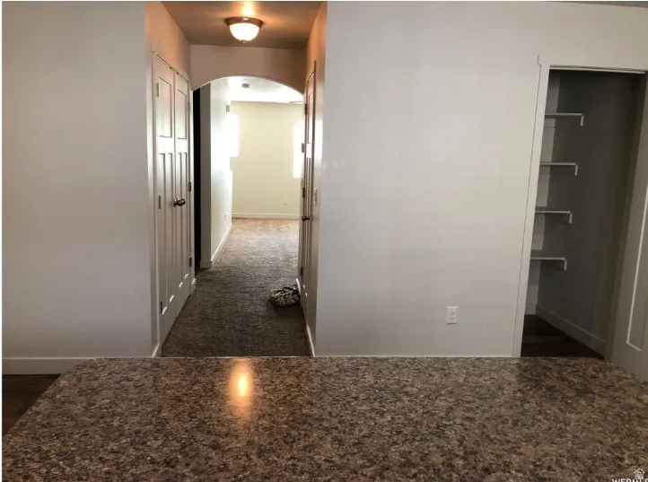 Corridor featuring arched walkways and dark colored carpet
