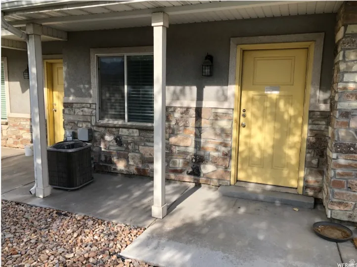 Entrance to property with stone siding, covered porch, and stucco siding
