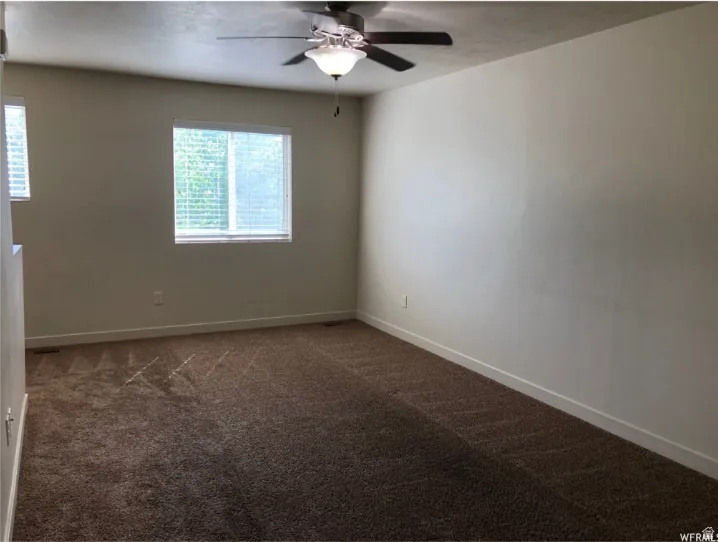 Spare room featuring dark carpet and ceiling fan