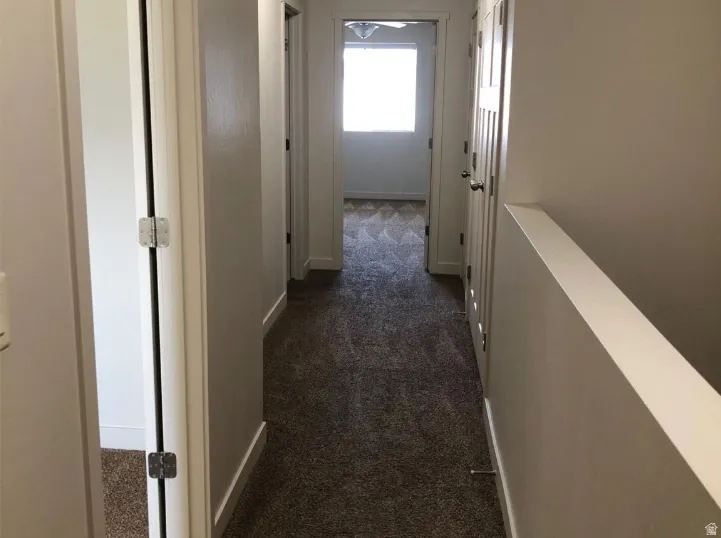 Corridor with dark colored carpet and baseboards
