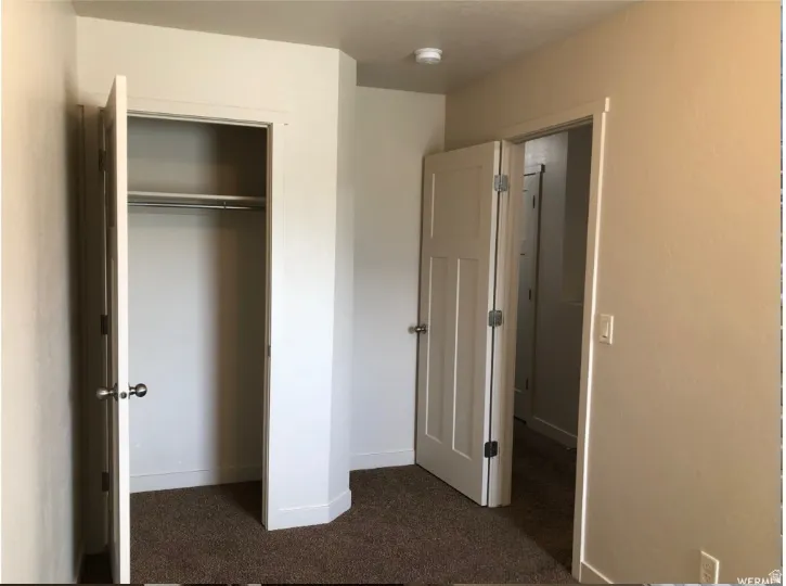 Unfurnished bedroom featuring dark colored carpet and a closet