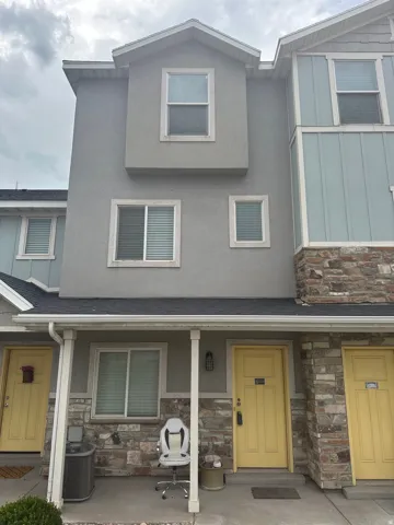 View of front of home featuring stone siding, roof with shingles, and stucco siding
