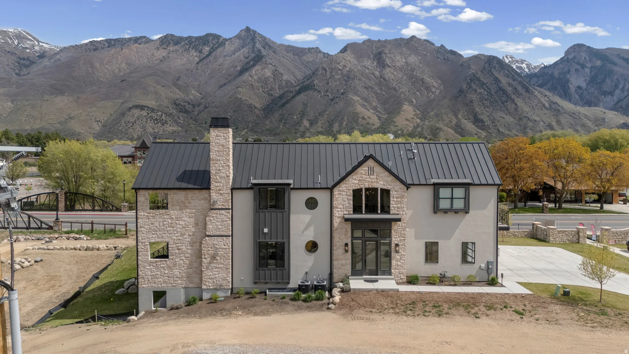 View of front of home with stone siding, a mountain view, a chimney, and a standing seam roof