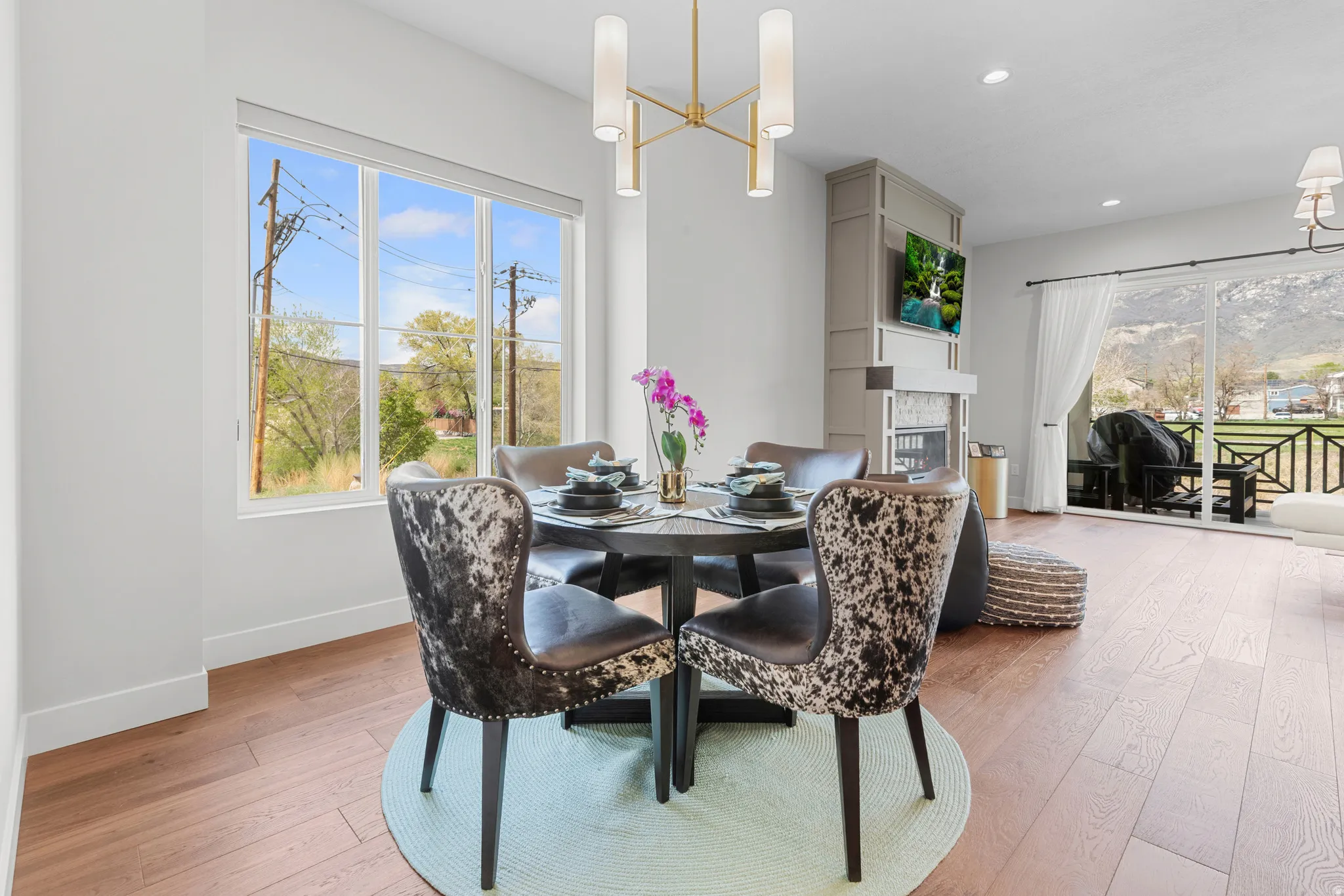 Dining area with suspended lighting, light wood-style floors, a glass covered fireplace, and healthy amount of natural light