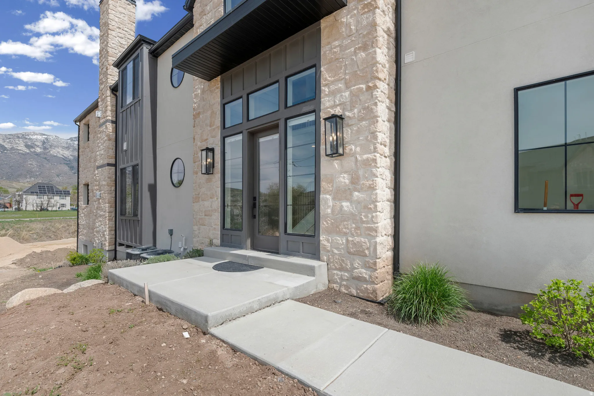 View of exterior entry featuring stone siding, a mountain view, and a chimney
