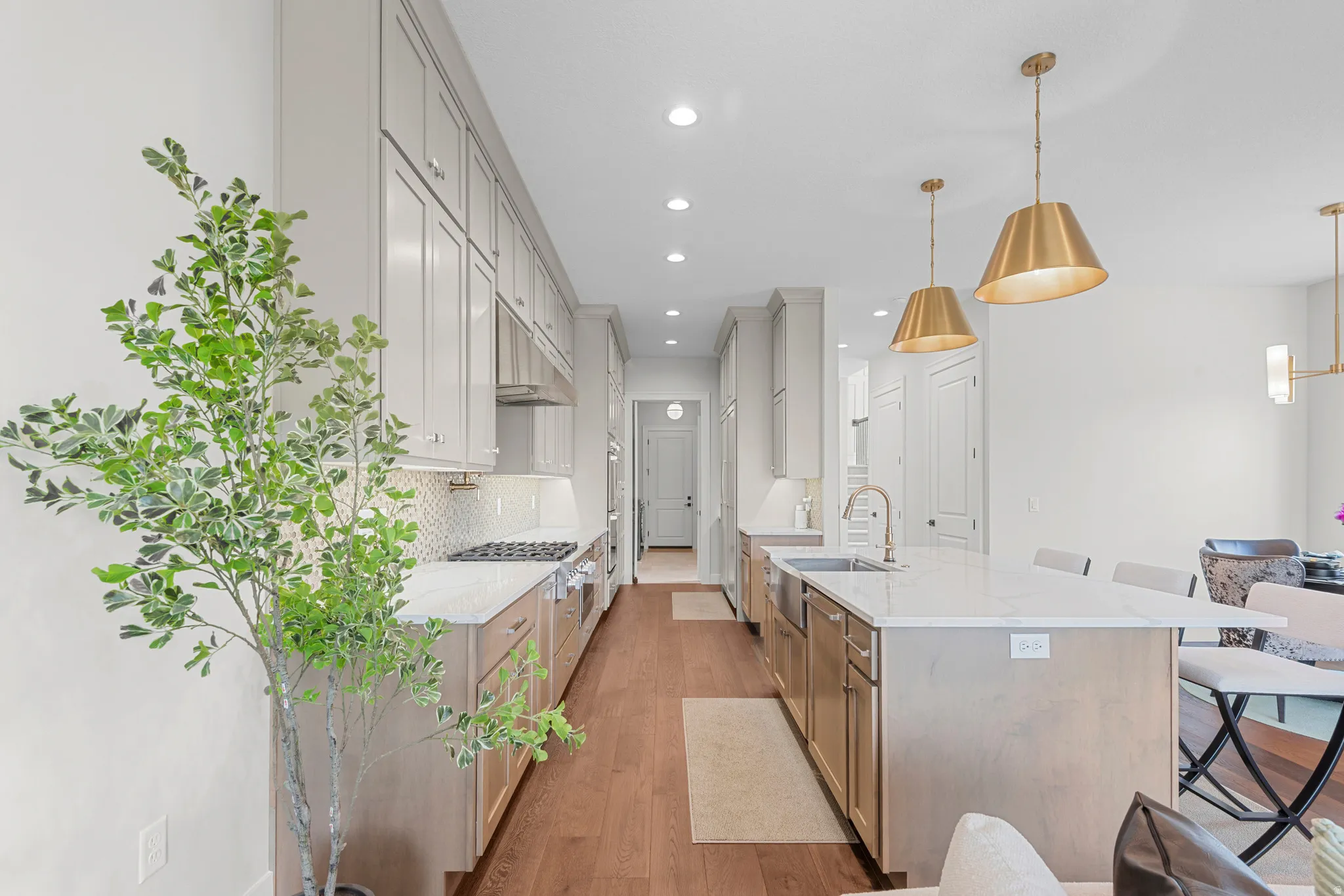 Kitchen featuring light stone countertops, a breakfast bar area, light wood-style floors, a spacious island, and tasteful backsplash