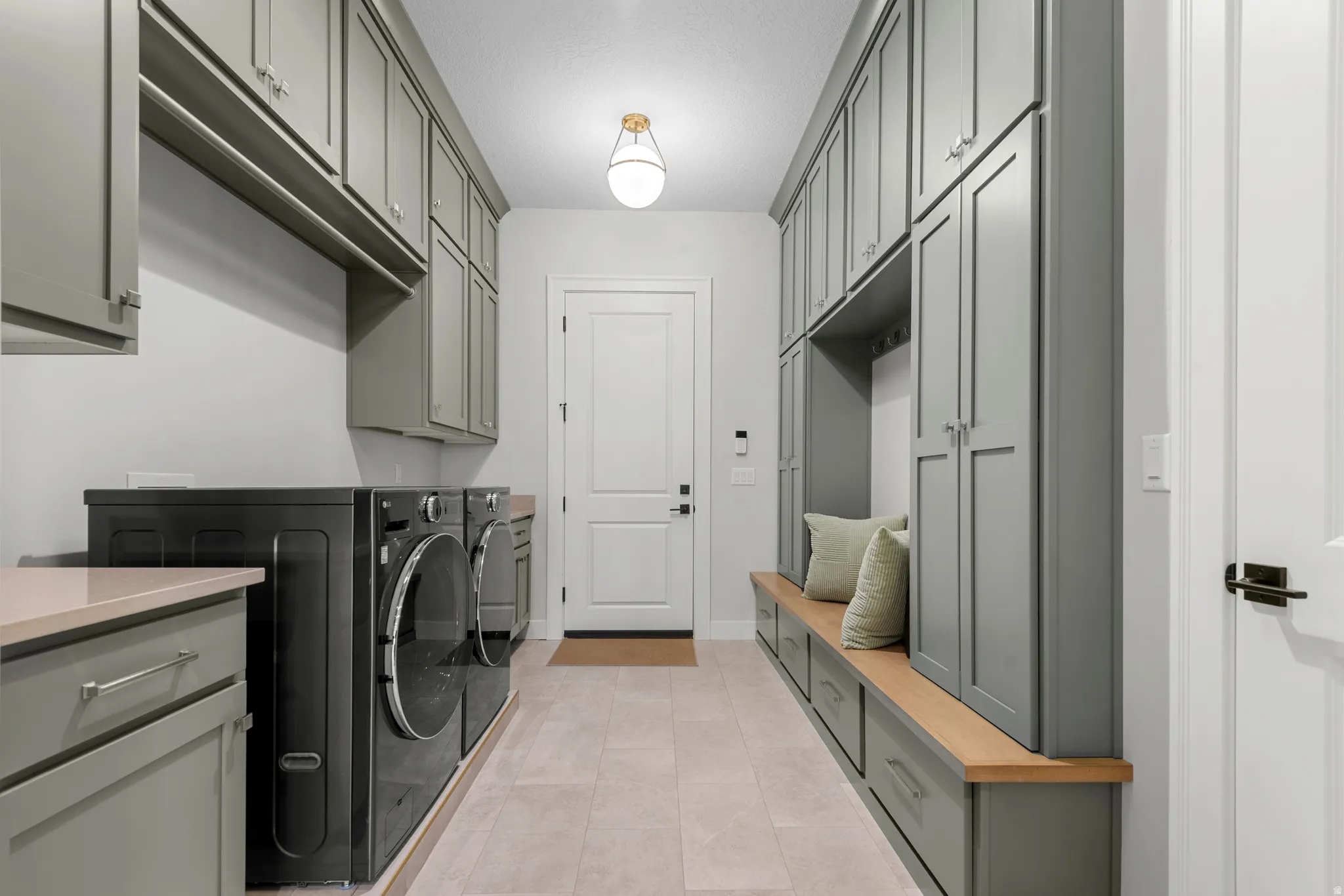 Laundry area with washing machine and clothes dryer, light tile patterned floors, and cabinet space