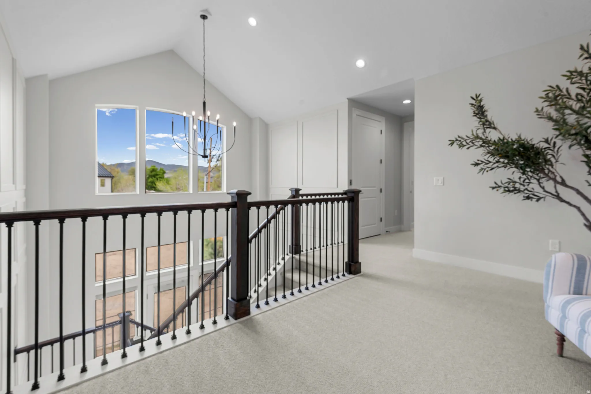 Hall with light colored carpet, an upstairs landing, suspended lighting, and a mountain view