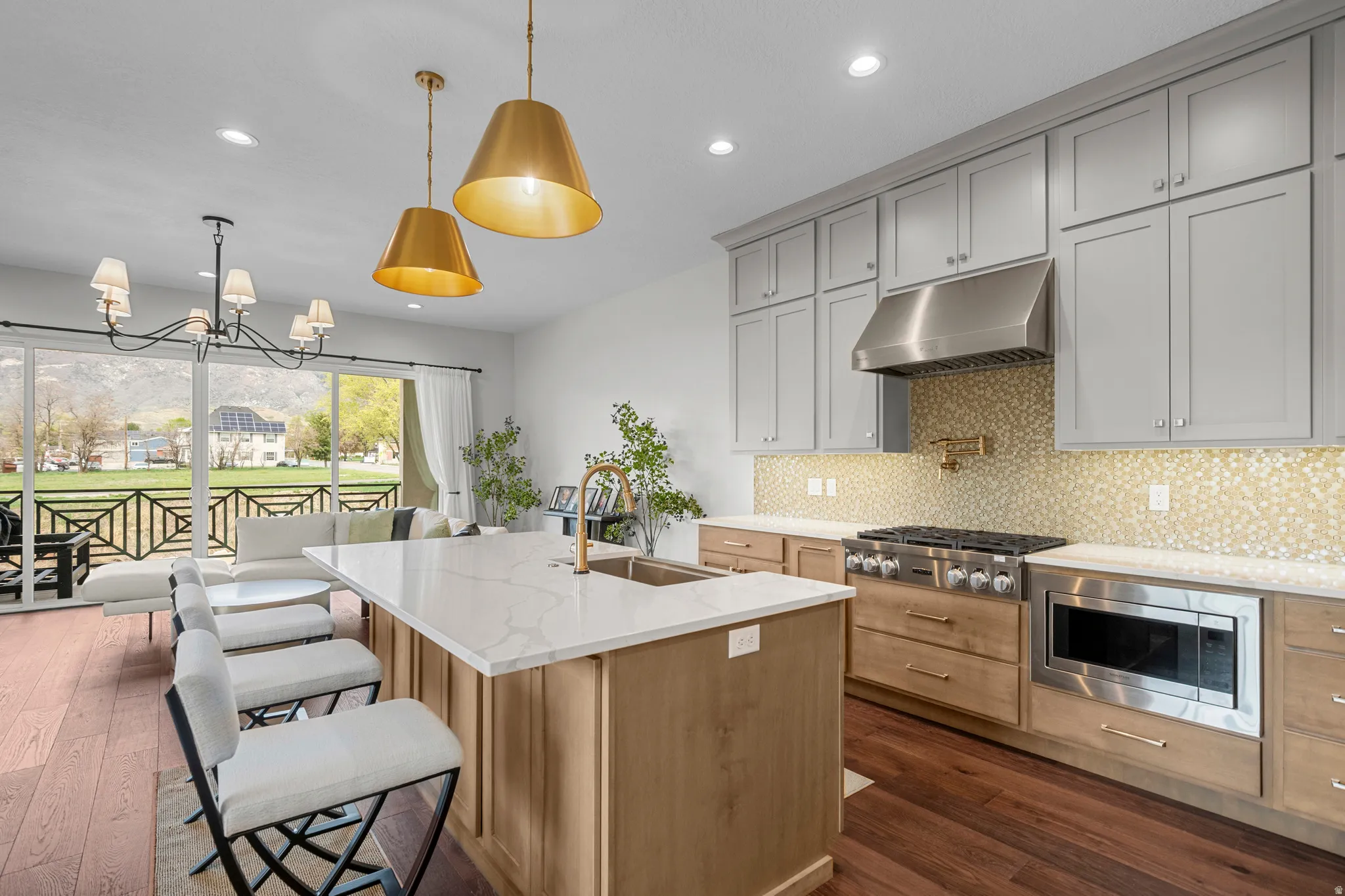 Kitchen featuring light stone countertops, a center island with sink, suspended lighting, stainless steel appliances, and backsplash