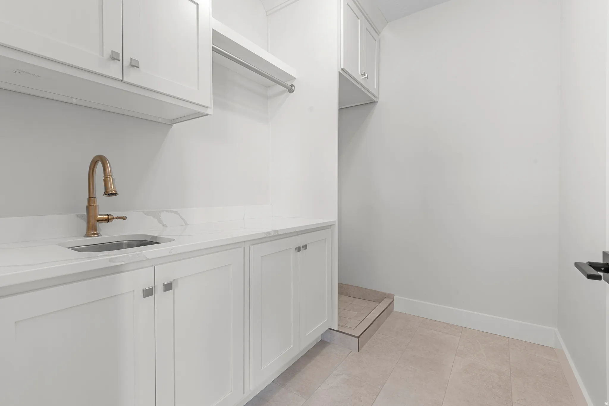 Laundry area with a sink and light tile patterned floors