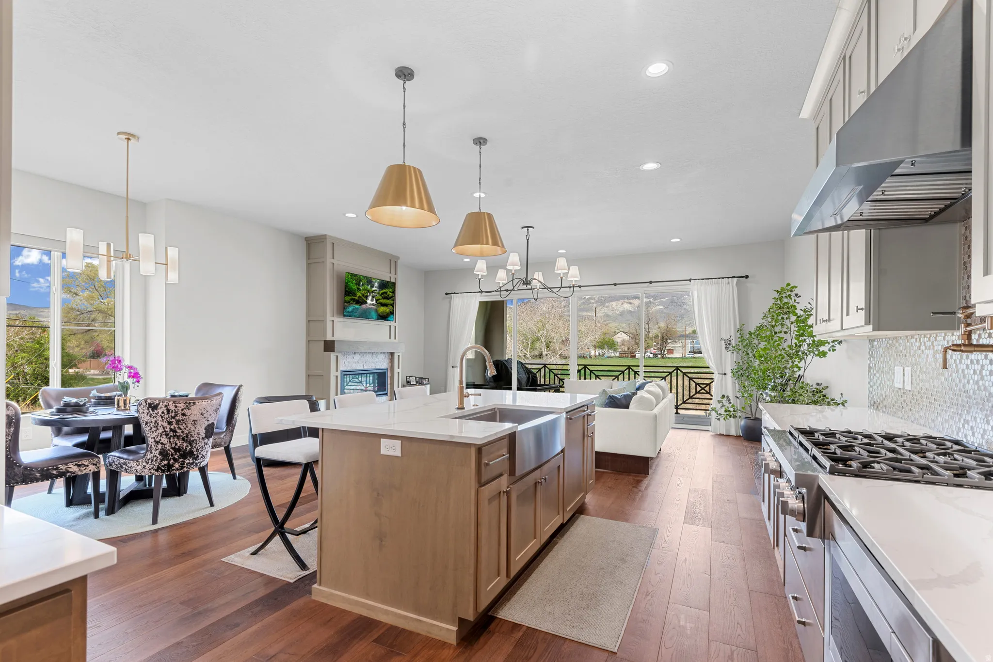 Kitchen with suspended lighting, dark wood-style floors, light stone countertops, open floor plan, and stainless steel appliances