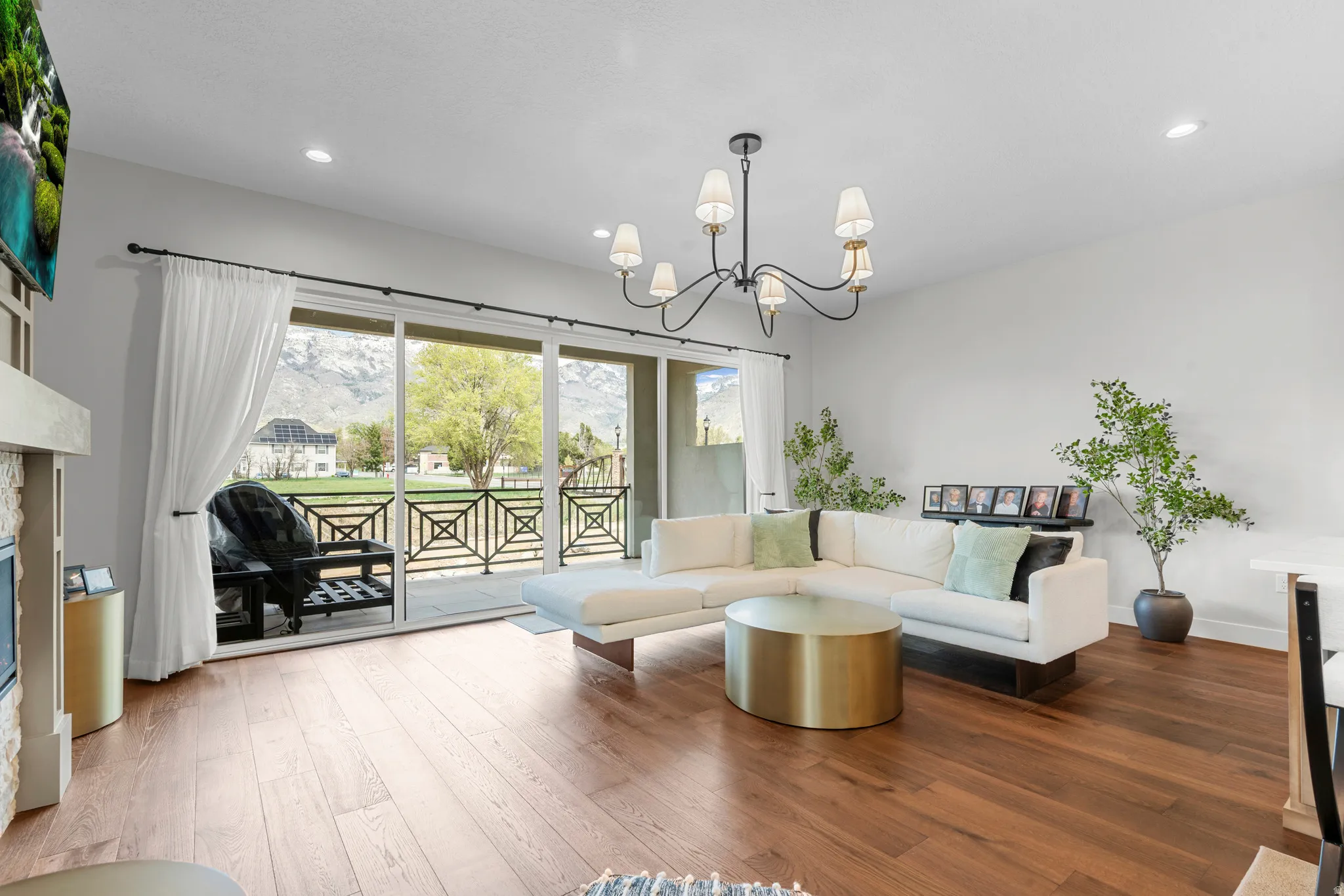 Living room with hanging lights, a glass covered fireplace, hardwood / wood-style floors, and a mountain view