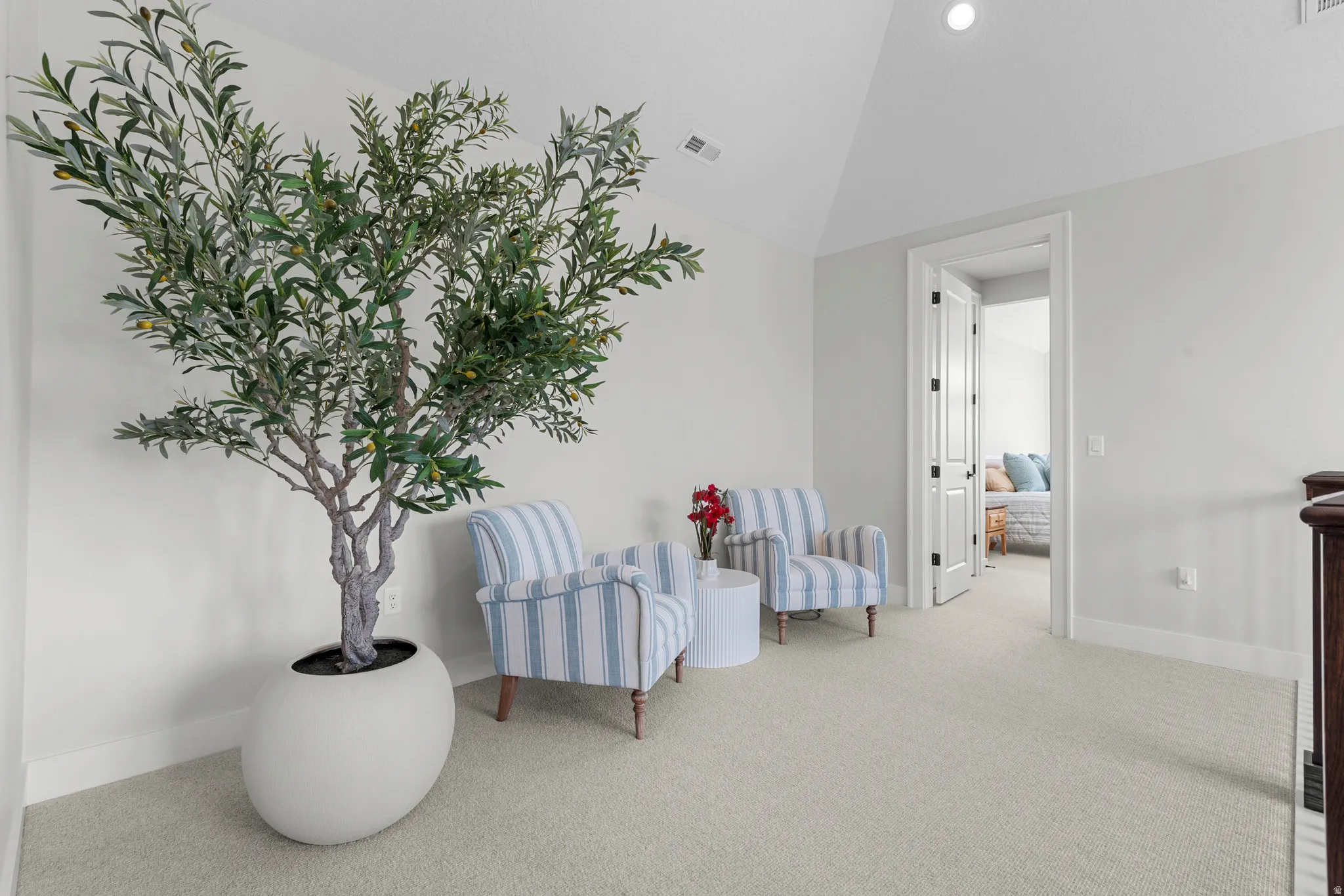 Living area with light carpet and vaulted ceiling