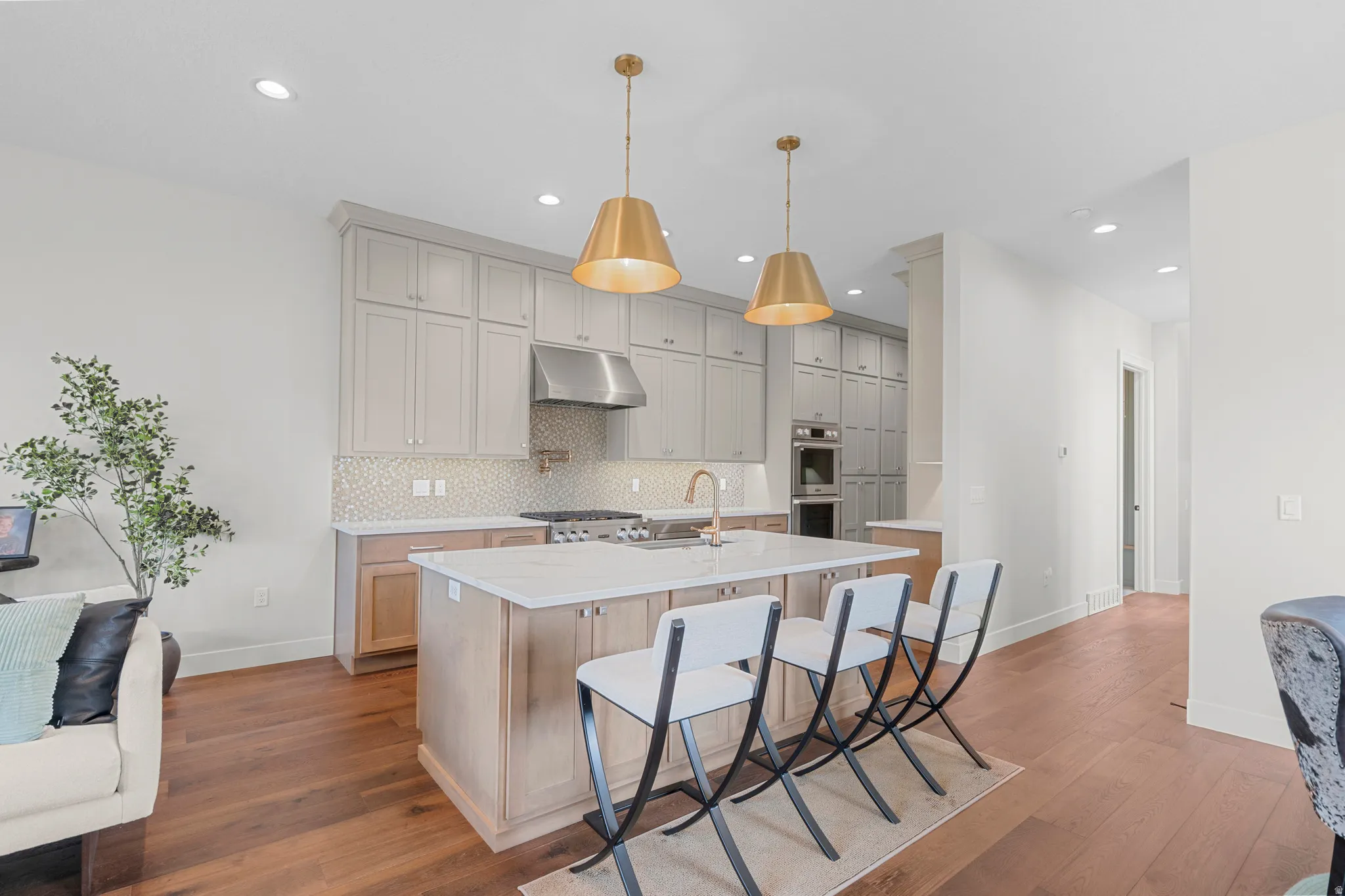 Kitchen with a breakfast bar, a kitchen island with sink, dark wood-style floors, and gray cabinets