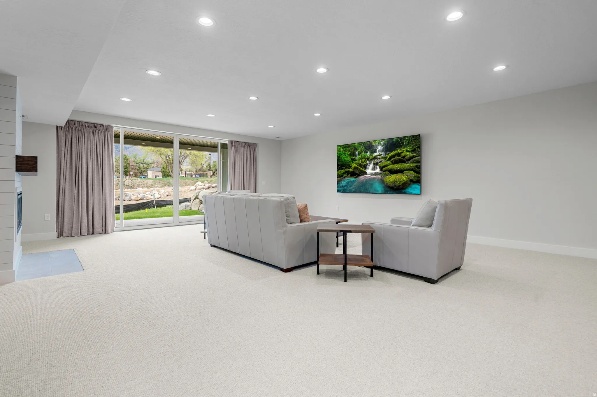 Living area with light carpet, recessed lighting, and a fireplace