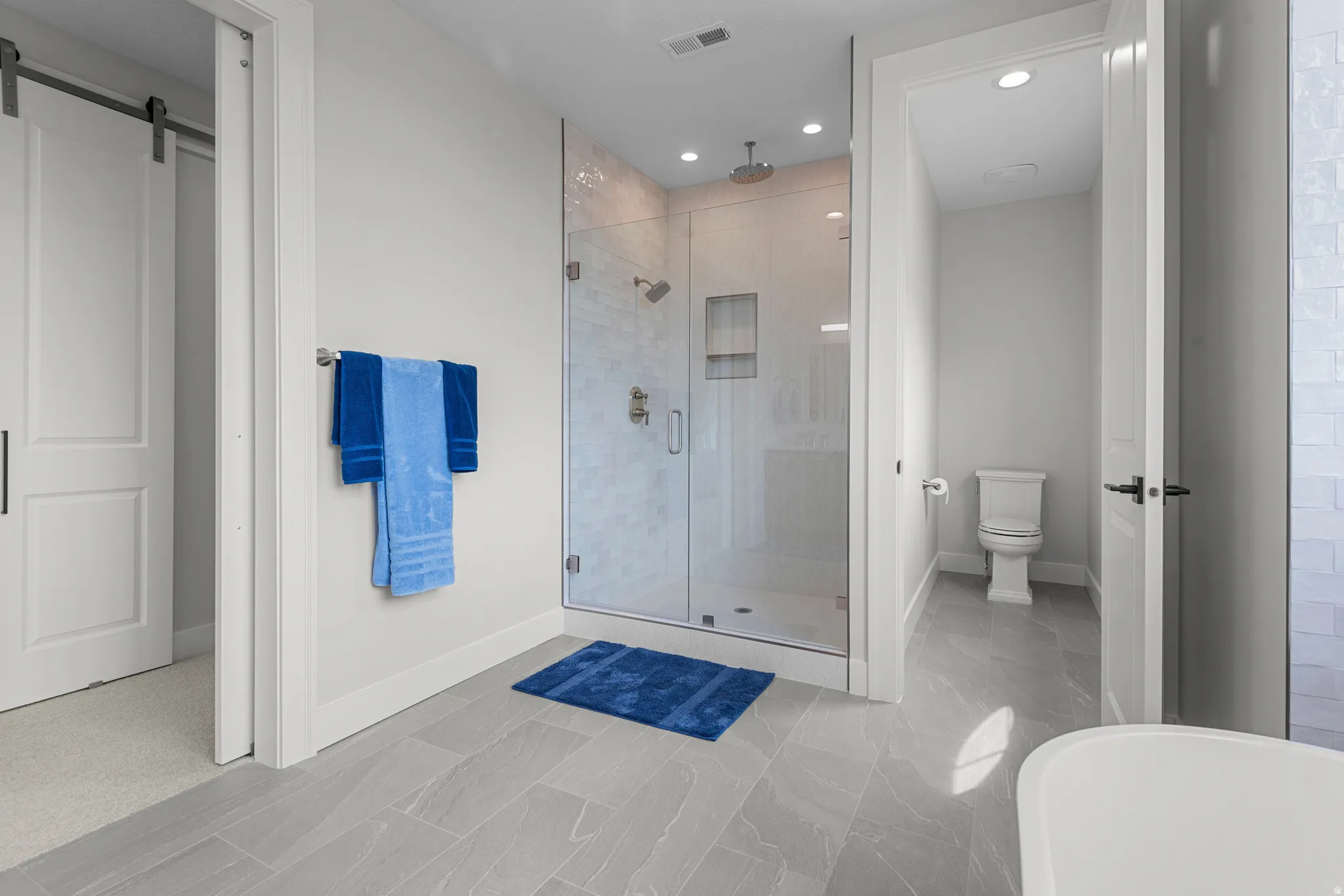 Full bathroom featuring a stall shower, a freestanding tub, and recessed lighting