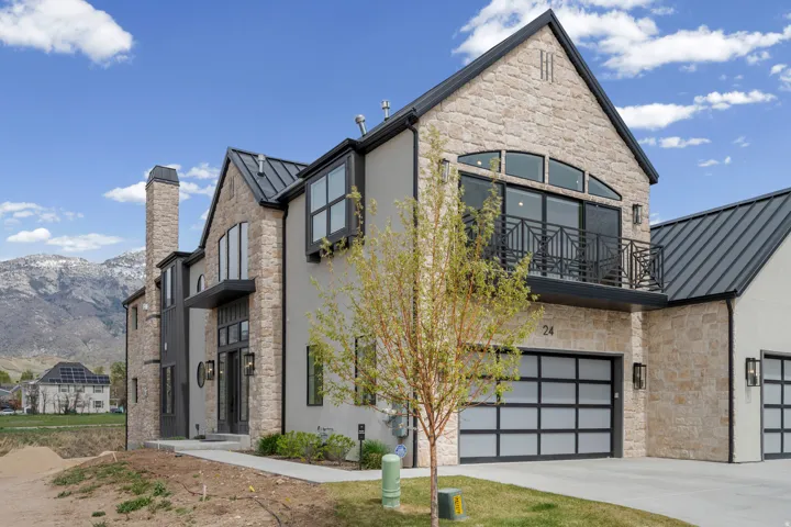 View of front of home featuring a standing seam roof, stone siding, a mountain view, and stucco siding