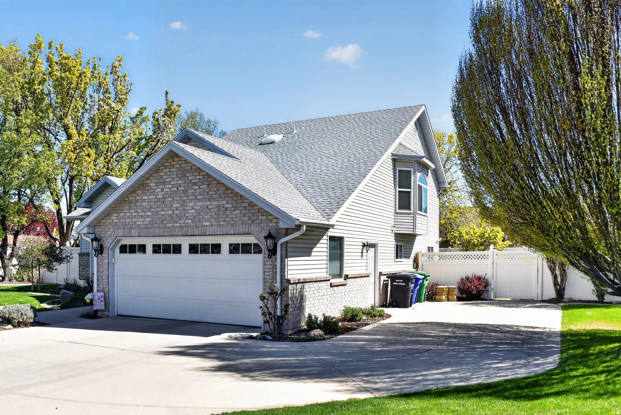 View of front of property with brick siding, a shingled roof, driveway, and an attached garage