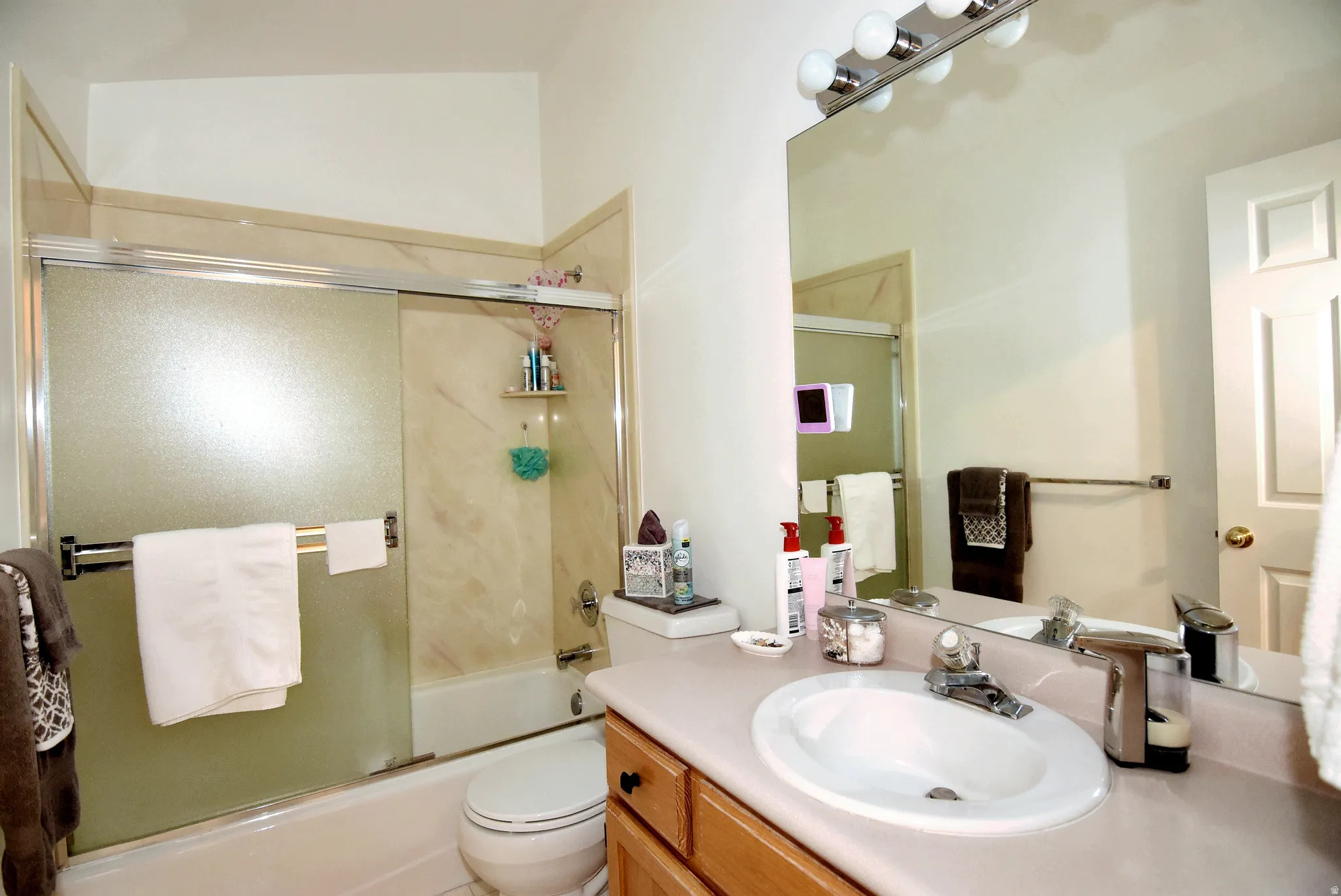 Bathroom with vanity and bath / shower combo with glass door