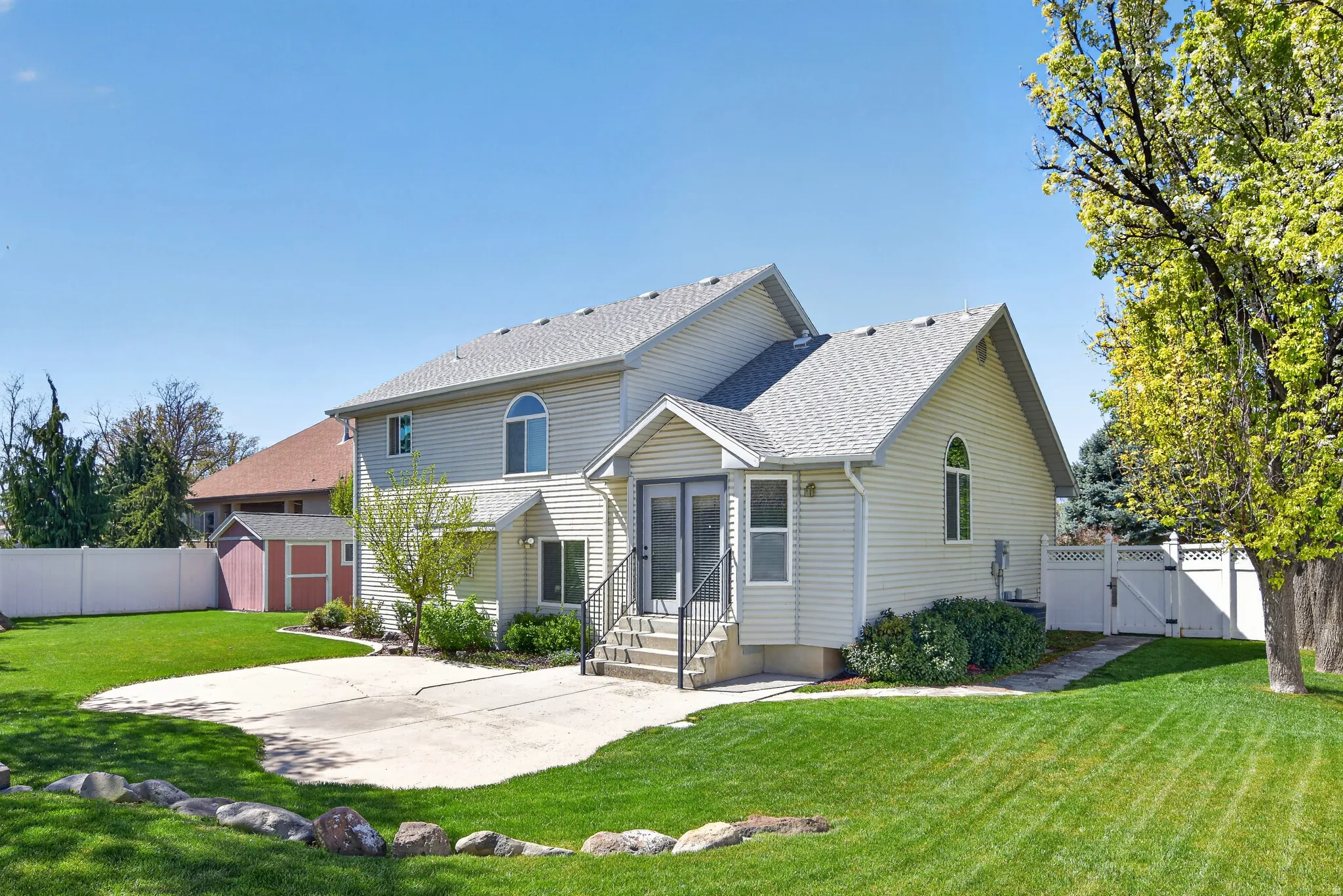 Back of house featuring a fenced backyard, a gate, roof with shingles, a storage shed, and entry steps