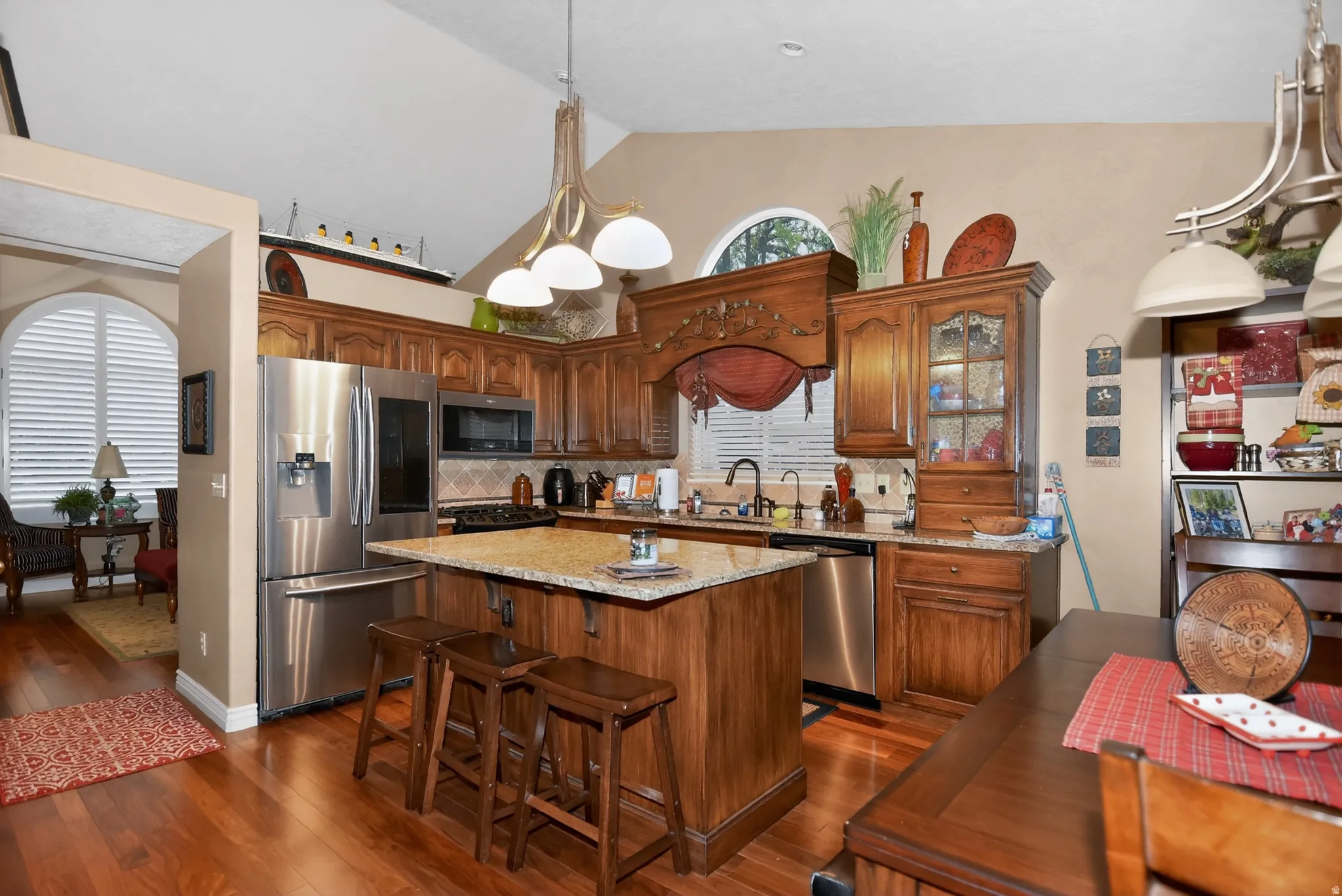 Kitchen with stainless steel appliances, light stone counters, a kitchen island, dark wood-type flooring, and a kitchen breakfast bar