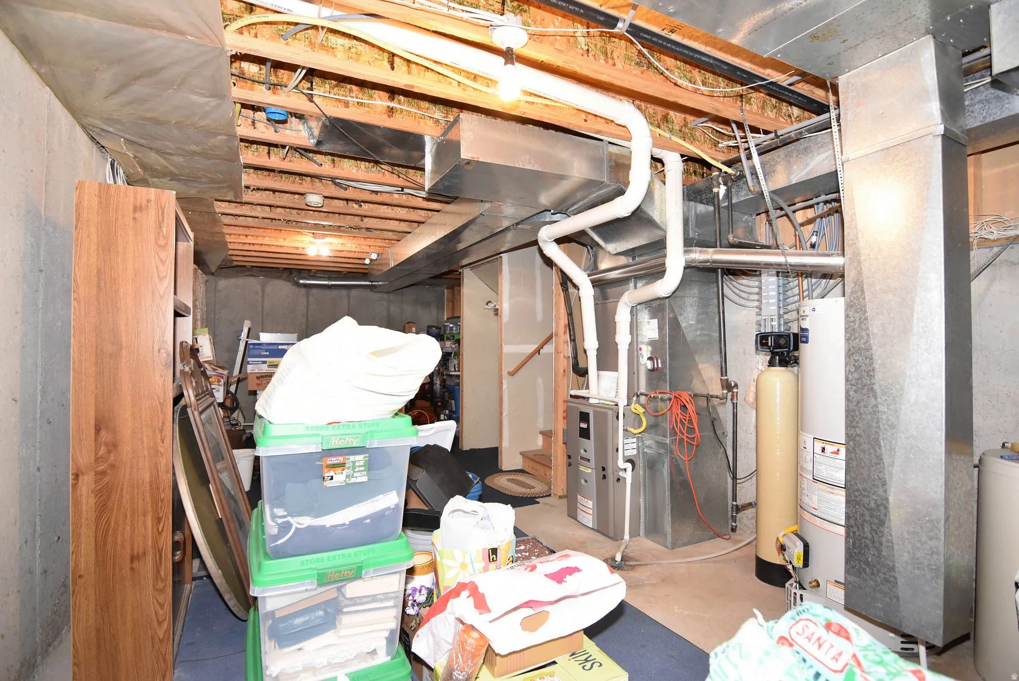 Unfinished below grade area with water heater, a water softener, and heating unit
