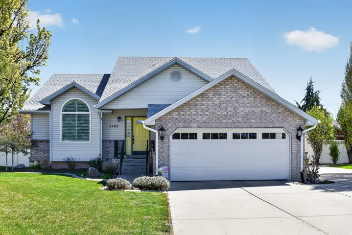 View of front facade with a front yard, an attached garage, concrete driveway, and a shingled roof