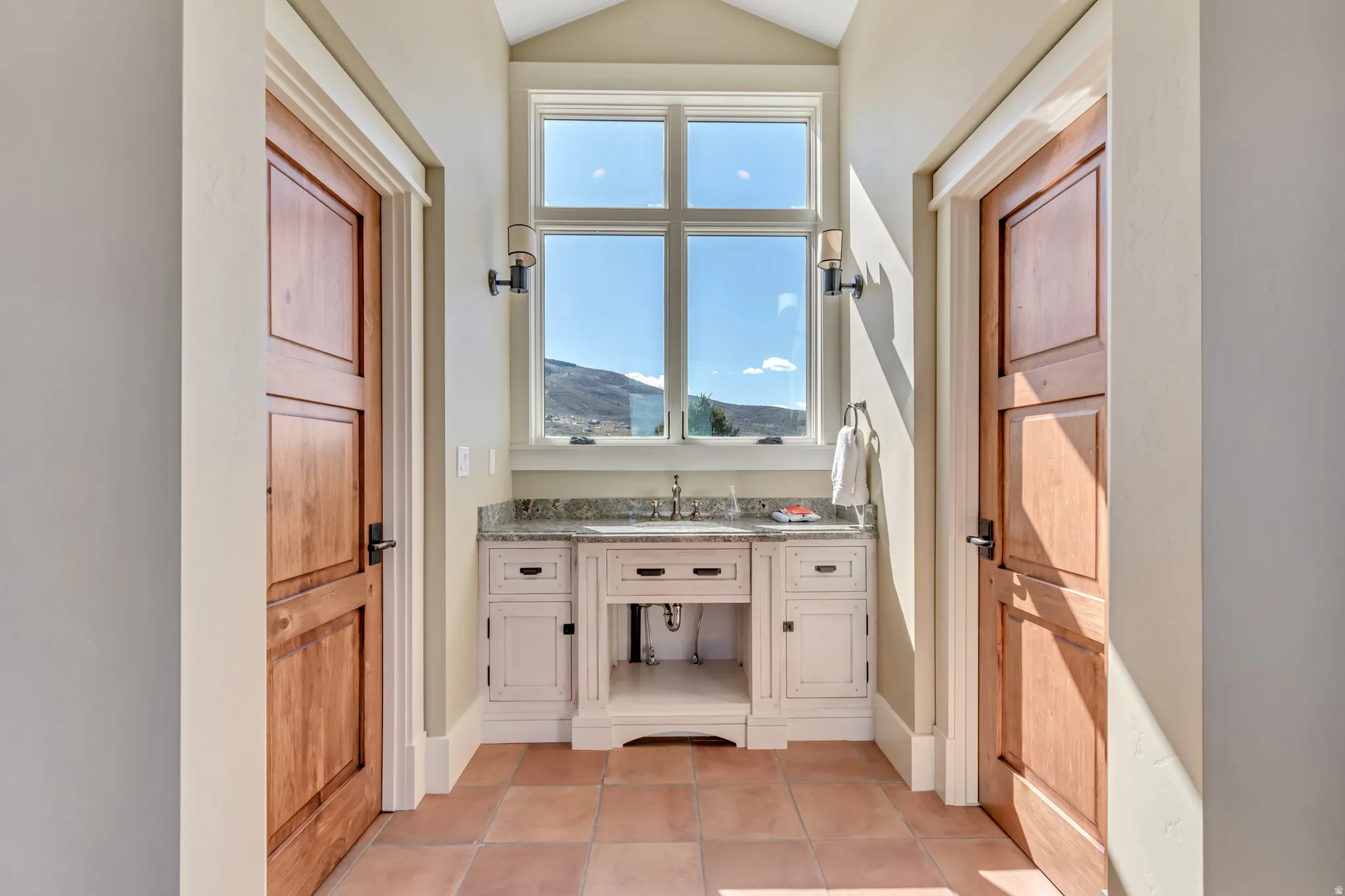 Bathroom featuring vanity, light tile patterned flooring, a mountain view, and lofted ceiling